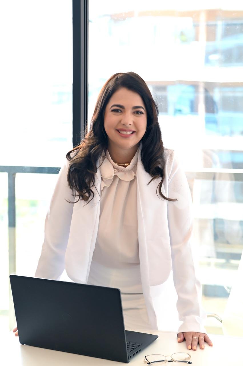 Dra. Andressa Fraga em pé atrás de uma mesa em seu consultório