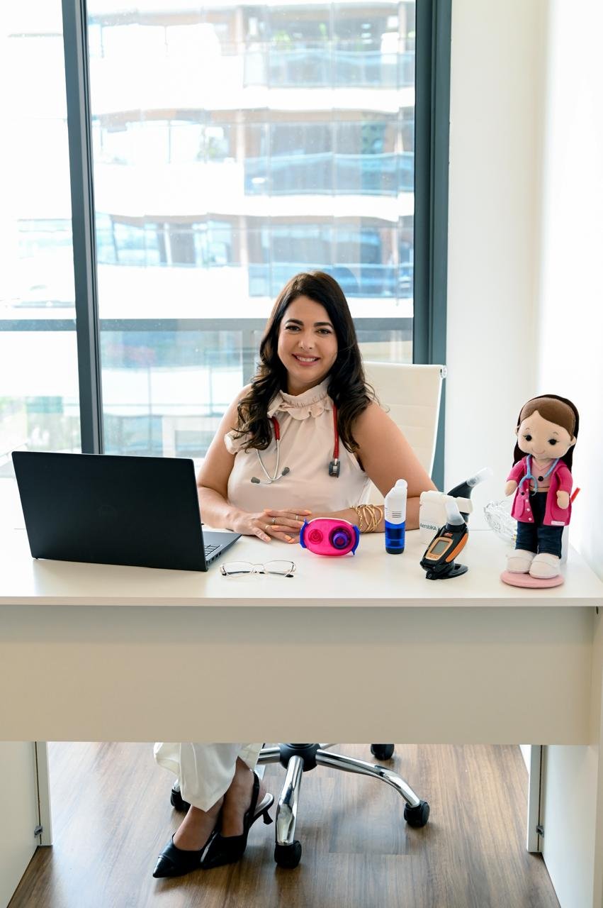 Dra. Andressa Fraga sentada à mesa com equipamentos respiratórios